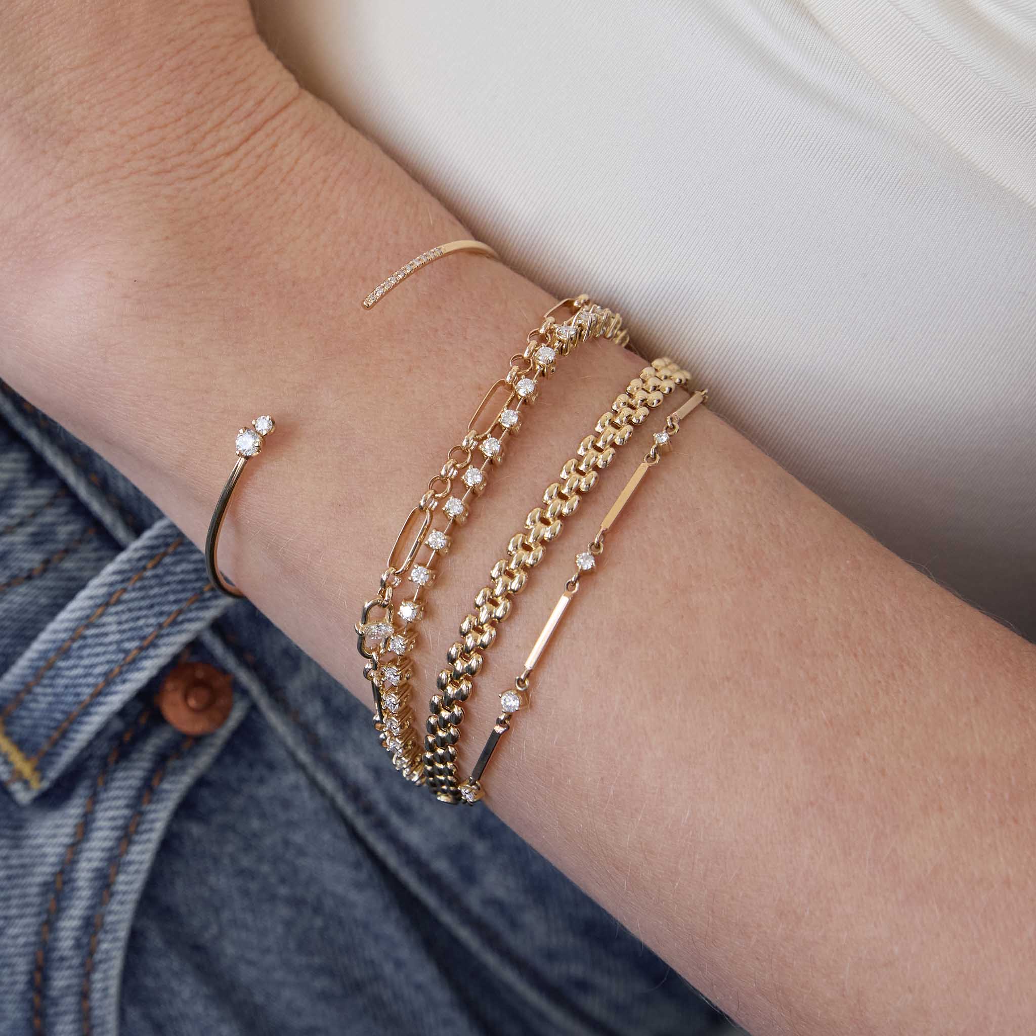 woman's wrist wearing a Zoë Chicco 14k Gold Prong Diamond Dash Tennis Bracelet stacked with a 14k Mixed Prong & Pavé Diamond Cuff, 14k Marquise Diamond Medium Paperclip Rolo Chain Bracelet, 14k Gold Small Panther Chain Bracelet, and a 14k Gold Bar & Graduated Prong Diamond Bracelet