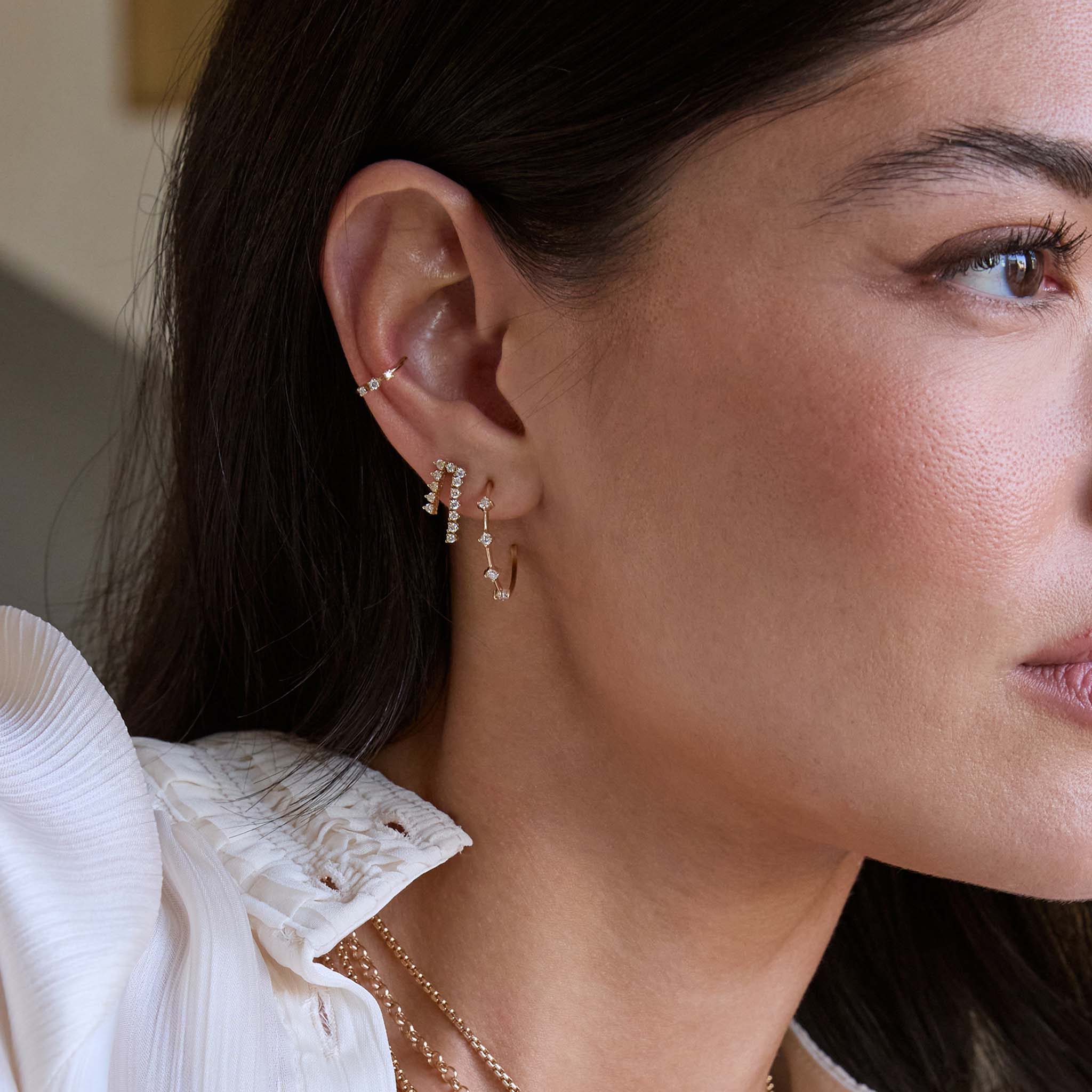 Close up of a woman wearing Zoe Chicco 14k old prong diamond hoops and tennis earrings