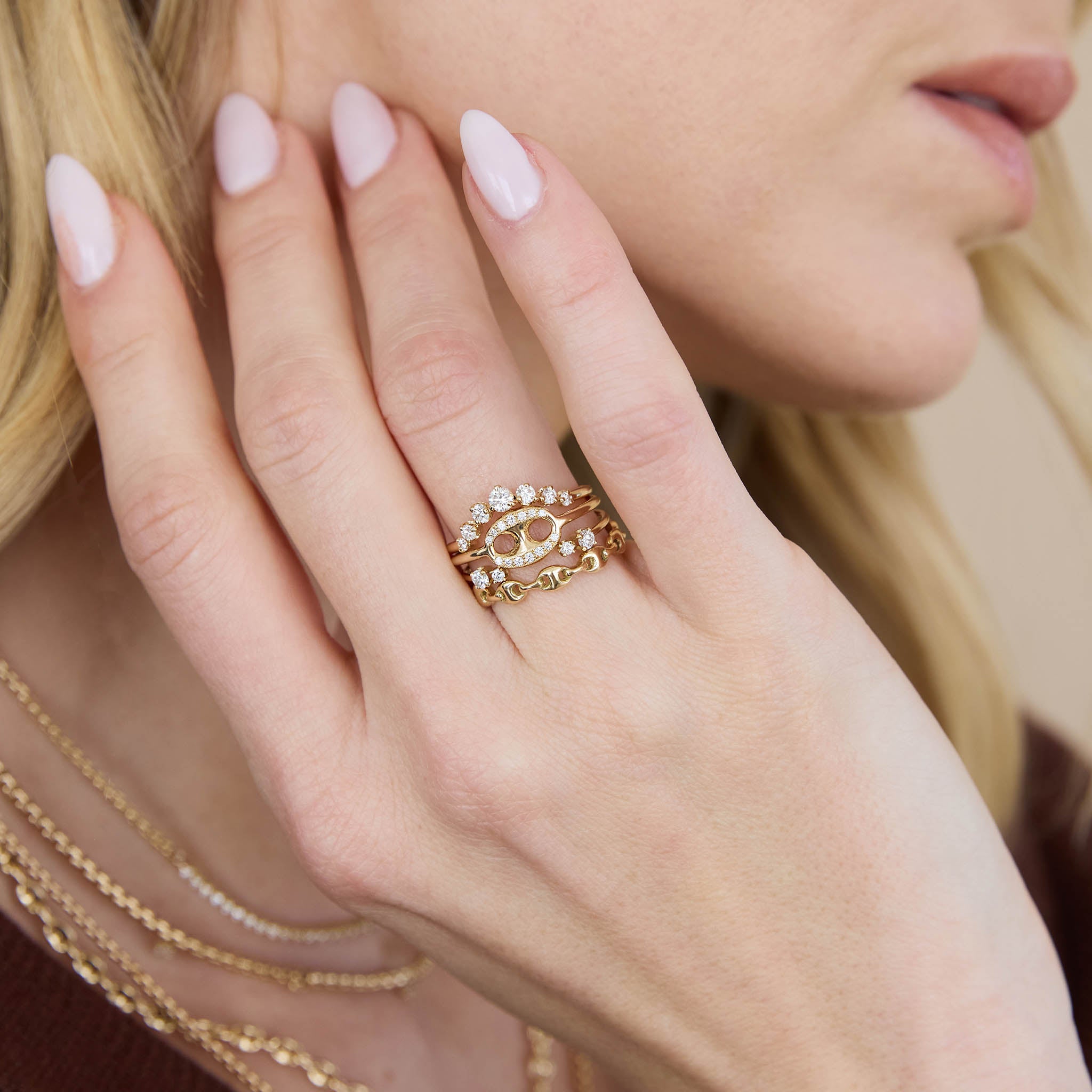 woman's hand resting against her neck wearing a Zoë Chicco 14k Gold Single Pavé Diamond Large Mariner Link Ring stacked with a 14k Graduated Prong Diamond Curved Bar Ring, 14k Double Mixed Prong Diamond Open Ring, and a 14k Gold Small Puffed Mariner Link Eternity Ring