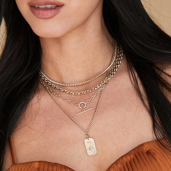 a close up of a woman wearing a Zoë Chicco 14k Gold Small Diamond Bezel Tennis Necklace layered with three other necklaces
