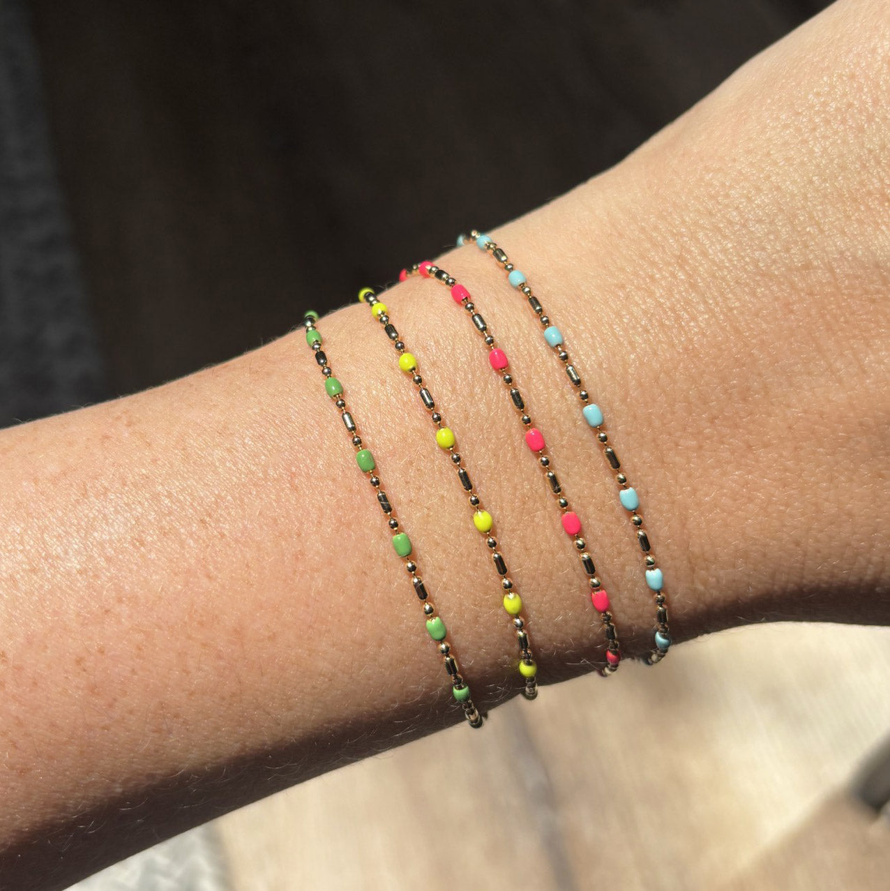 A model is wearing Zoe Chicco's 14k Gold Enamel Chain Bracelet in Turquoise, Neon Pink, Neon Yellow and Green.