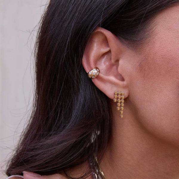 Close-up of a person wearing a Zoe Chicco 14k gold and star set diamond ear cuff with a puffed round waterfall chain earring with a neutral background