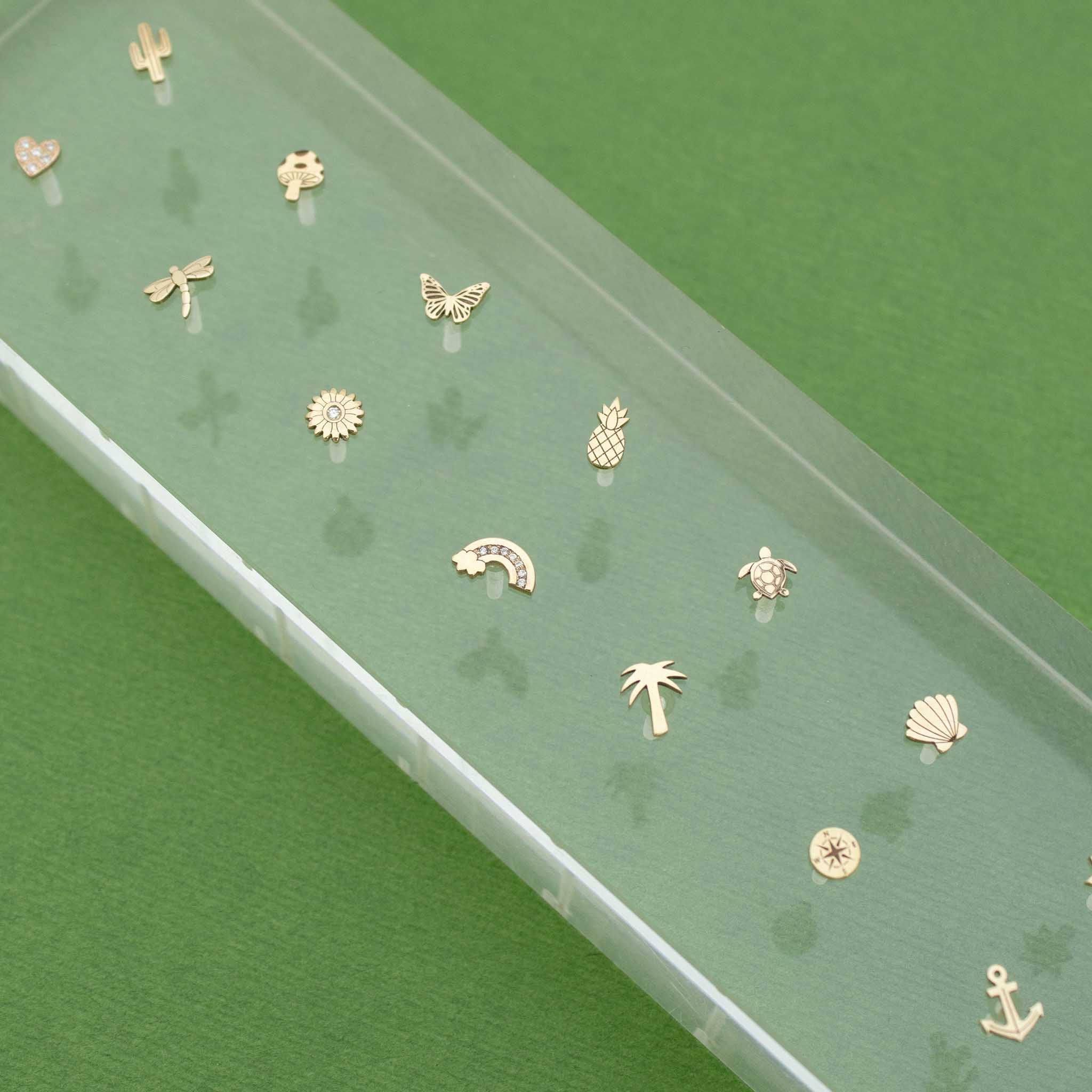 Gold Itty Bitty Symbol Studs on a Green Background