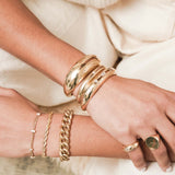 woman with her arms in her lap wearing a Zoë Chicco 14k Gold Single Star Set Diamond Small Aura Cuff Bracelet stacked with two other aura cuff bracelets on her wrist