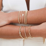 a woman with her arms crossed on top of each other wearing a Zoë Chicco 14k Gold 5 Prong Diamond Small Puffed Mariner Chain Bracelet with a stack of bracelets on each wrist