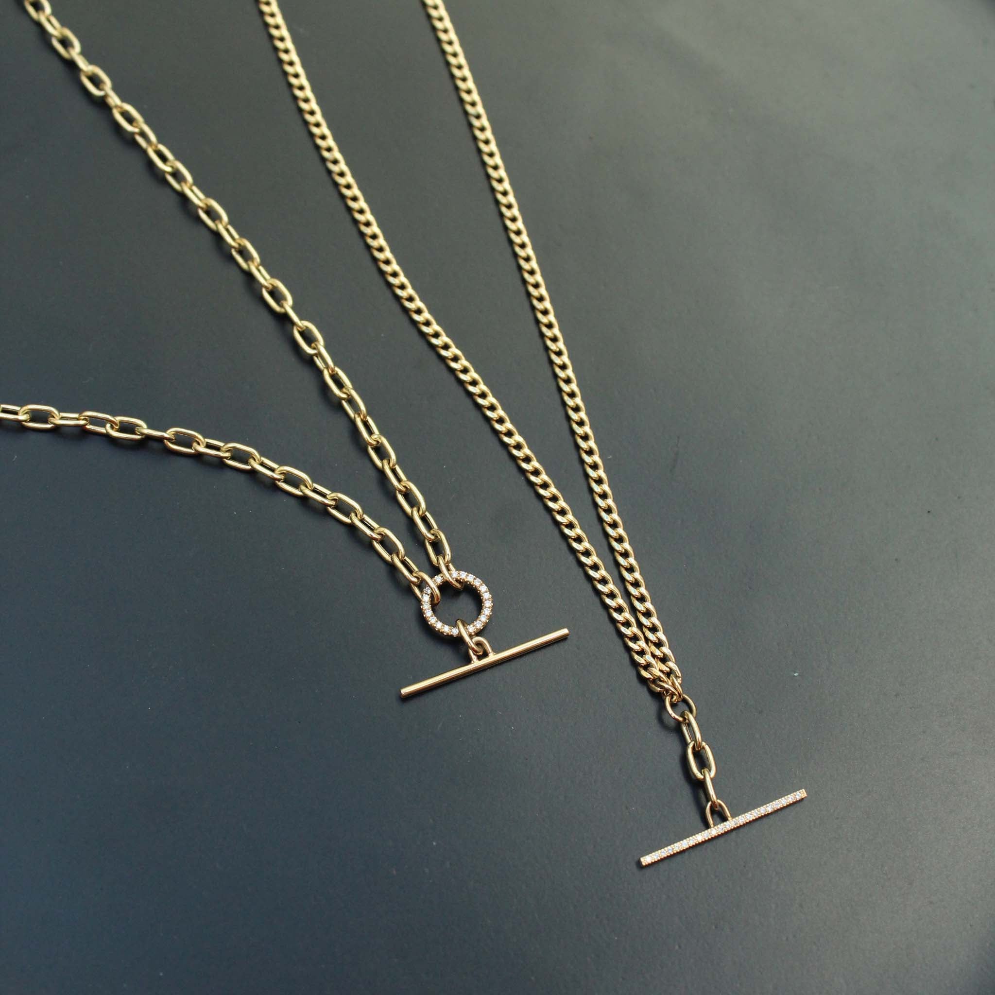 a Zoë Chicco 14k Gold Mixed Small Curb & Medium Square Oval Chain Pavé Diamond Toggle Lariat Necklace laying flat against a dark background