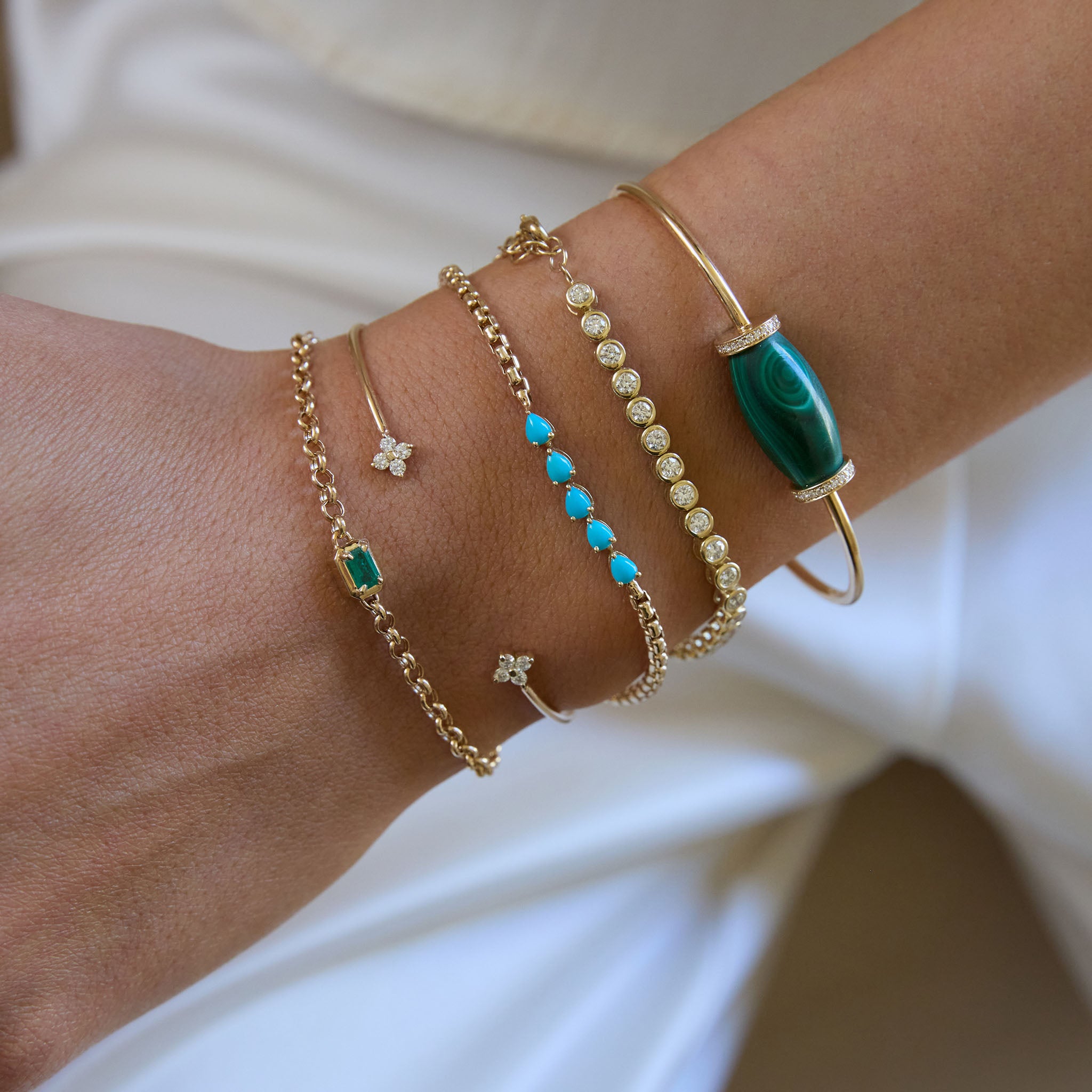 Zoe Chicco 14k gold and diamond stacked bracelets paired with turquoise and malachite gemstone bracelets worn on a wrist against a neutral background