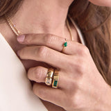 woman's hand wearing a Zoë Chicco 14k Gold One of a Kind .90 ctw Emerald Cut Diamond Half Round Band Ring and one of a kind emerald ring on her ring finger and a Zoë Chicco 14k Gold Pear Emerald & Pavé Diamond Open Ring on her index finger