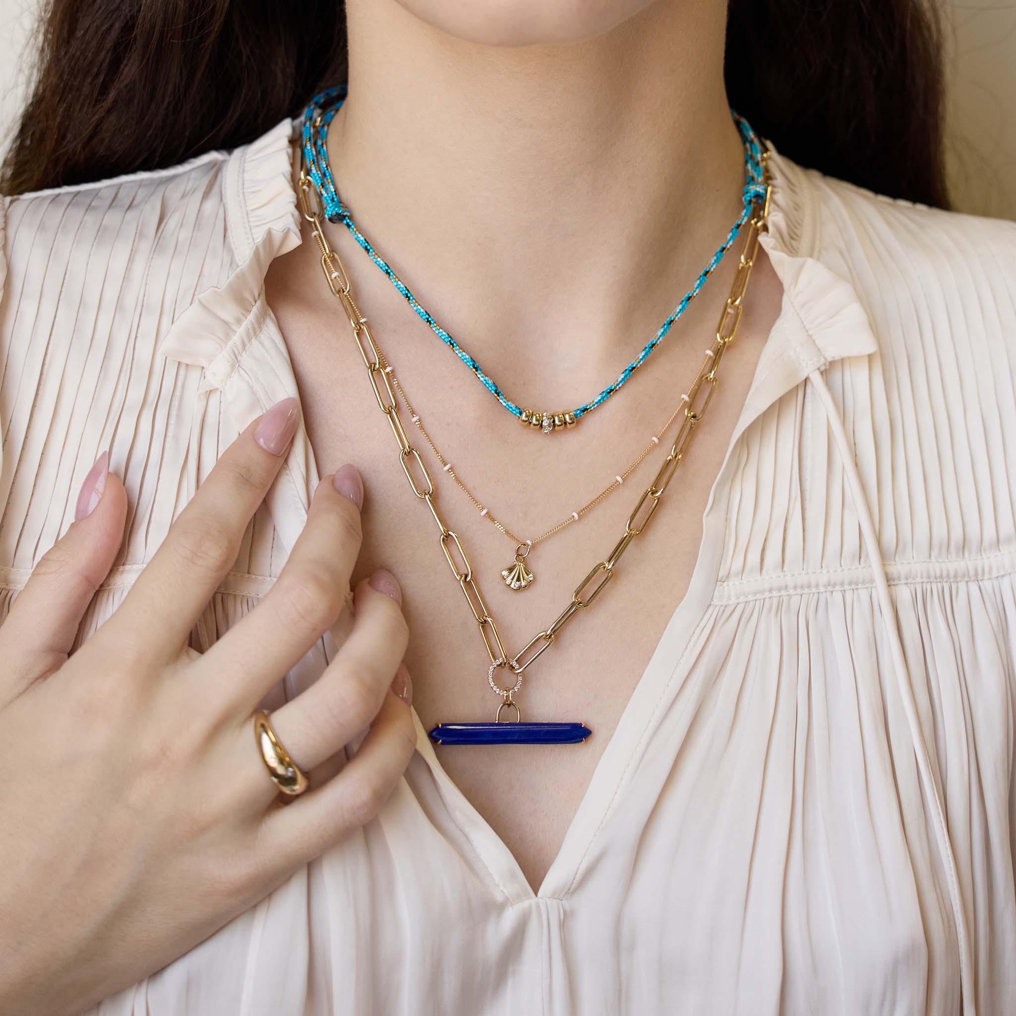 Person wearing multiple necklaces with a focus on hand and jewelry featuring 14k Lapis Bar & Pavé Diamond Circle Large Paperclip Chain Necklace