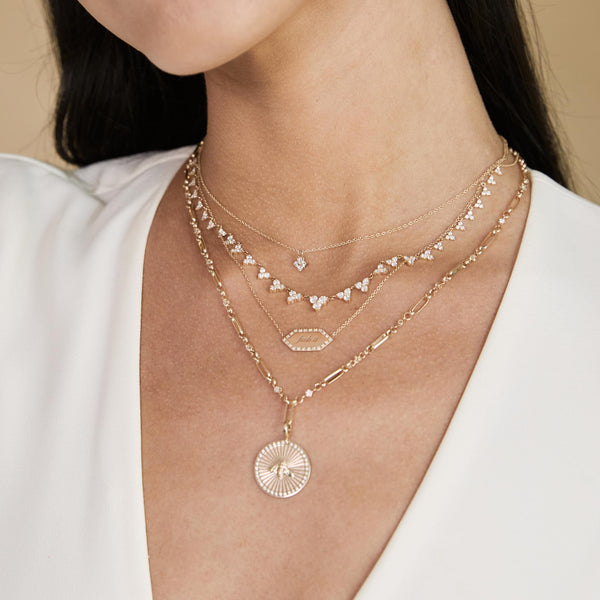 a woman in an ivory blouse wearing a Zoë Chicco 14k Gold Prong Diamond Quad Necklace layered with three other necklaces