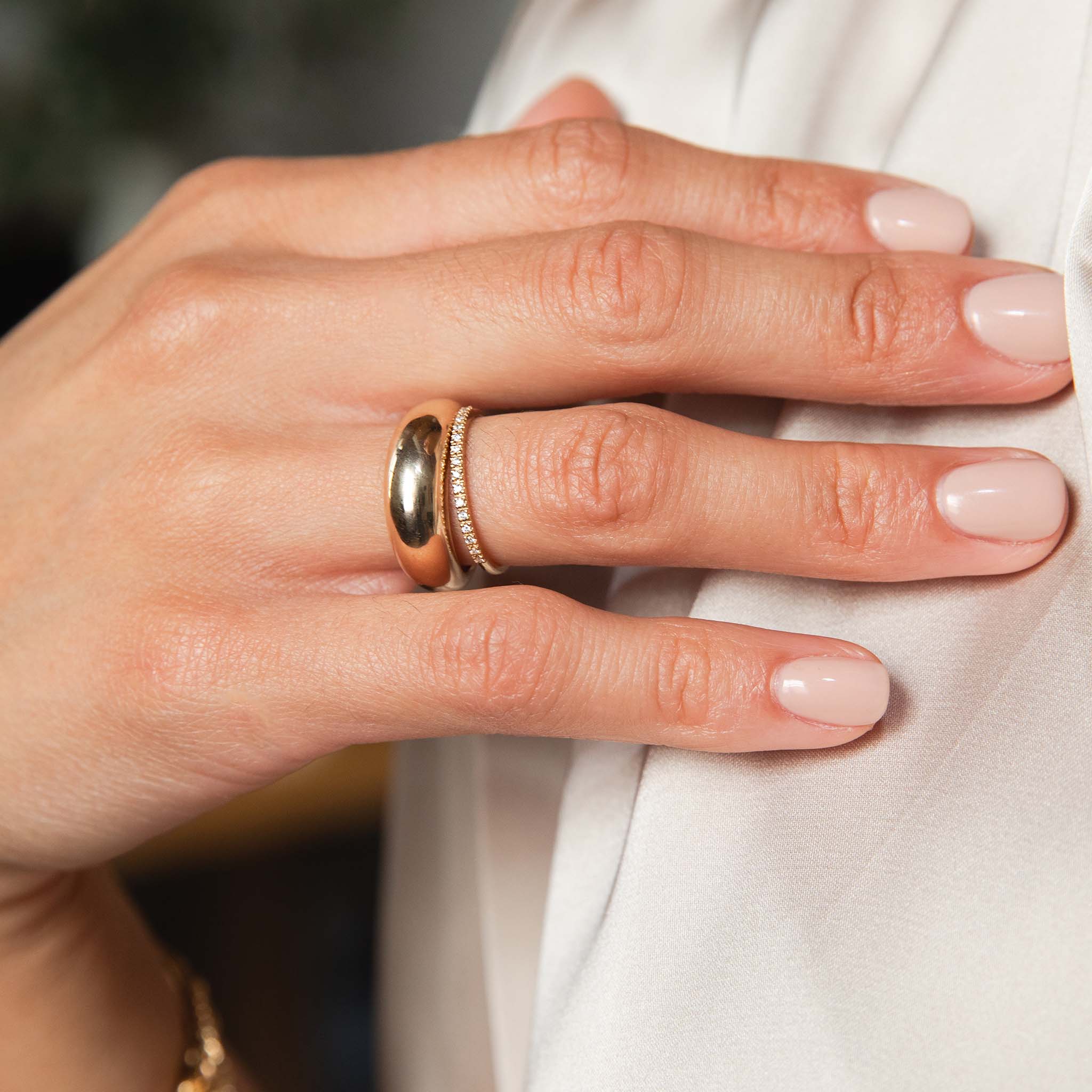 A woman is showing off her ring stack of a single plain Aura ring and our half pave diamond eternity band.