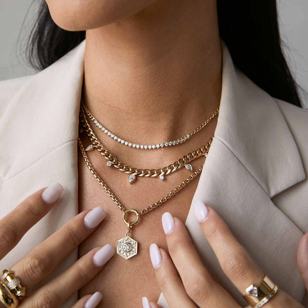a woman in a beige blazer wearing a Zoë Chicco 14k Gold Diamond Hexagon Halo Pendant Large Box Chain Necklace layered with two necklaces