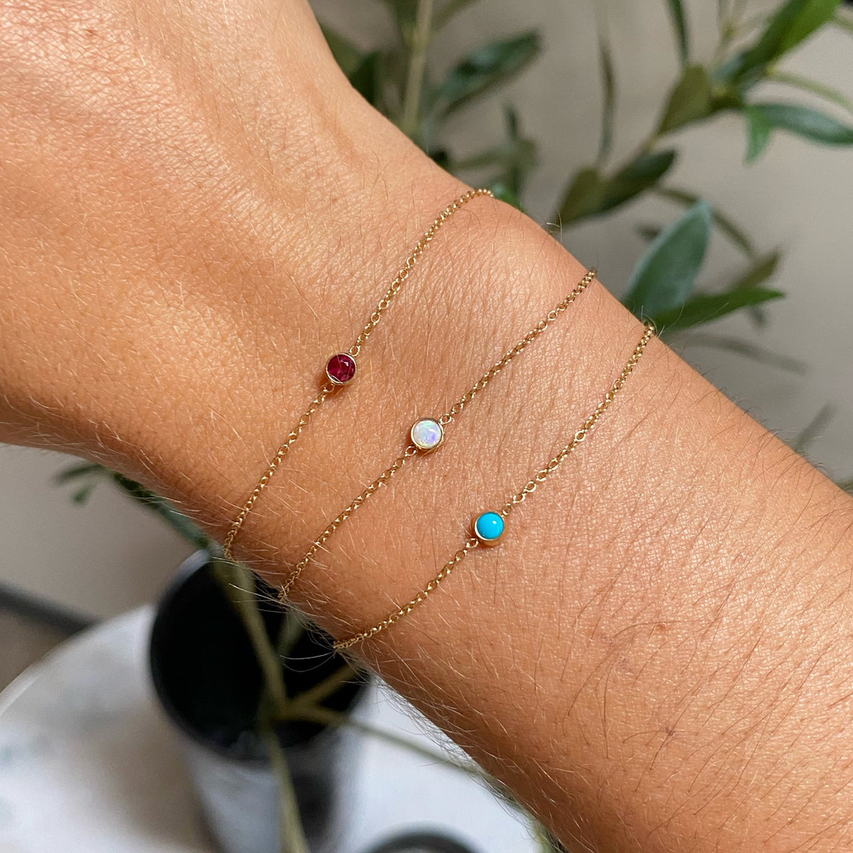 woman's wrist wearing Zoe Chicco 14kt Gold Single Bezel Opal Bracelet stacked with a Ruby Bezel Bracelet and Turquoise Bezel Bracelet