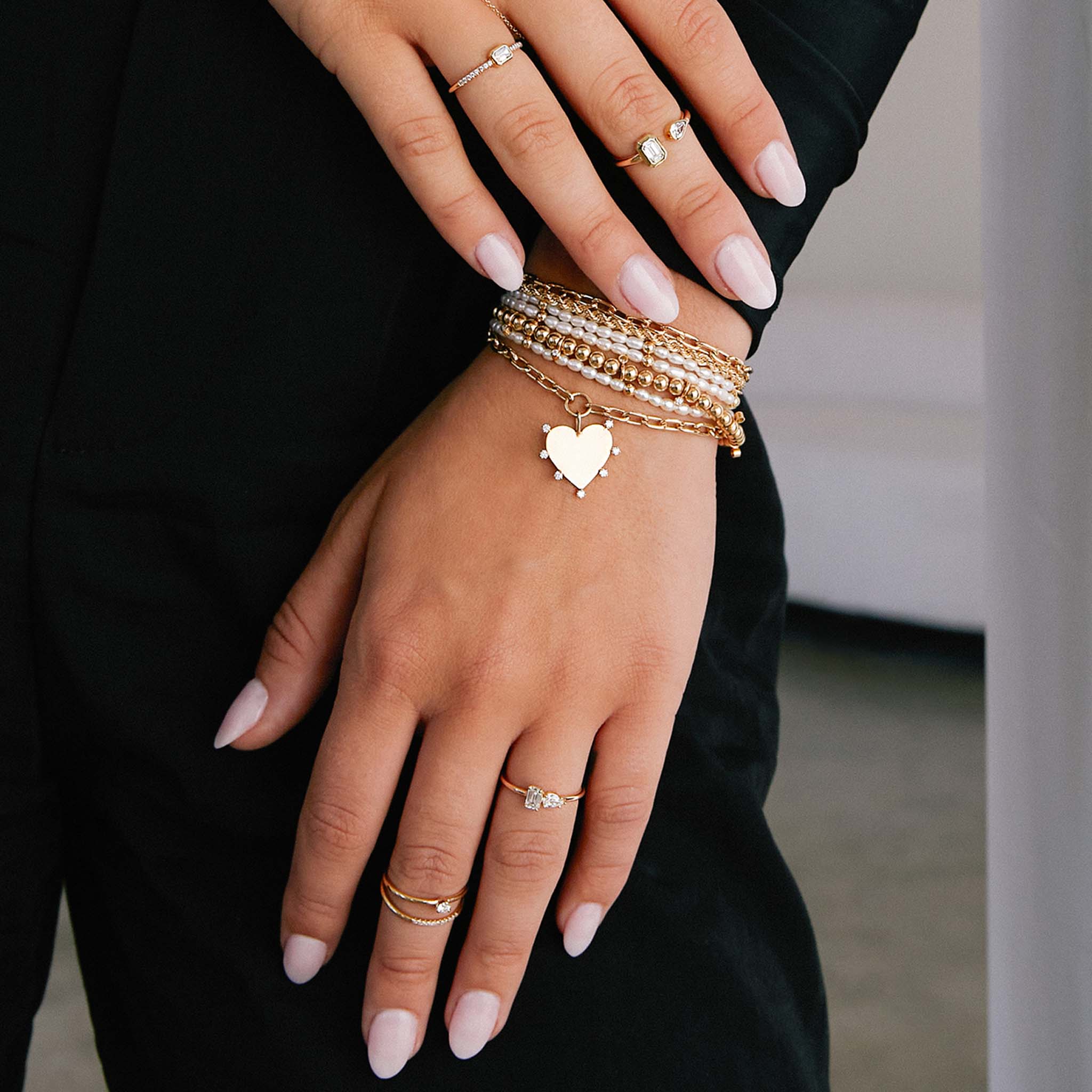 woman's wrist wearing a Zoë Chicco 14k Gold Bead & Rice Pearl Triple Wrap Convertible Bracelet resting on her leg