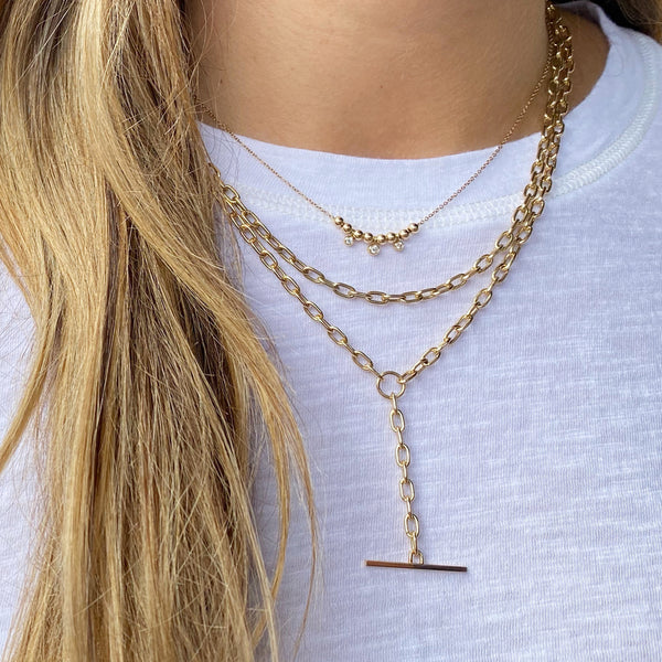 woman in white t-shirt wearing Zoë Chicco 14kt Gold Medium Square Oval Link Chain Necklace layered with a Large Square Oval Link Toggle Necklace