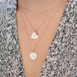 woman in grey sweater wearing two Zoë Chicco 14kt Gold Tiny Bar and Cable Chain Necklaces layered together with charms dangling from them and a single floating diamond necklace