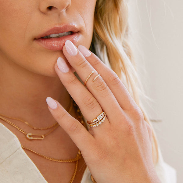 Woman holding her hand up to her mouth wearing a Zoë Chicco 14k Gold Pavé and Prong Diamond Bypass Ring on her middle finger
