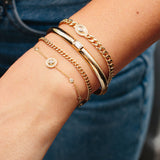woman's wrist with a stack of four gold and diamond bracelets