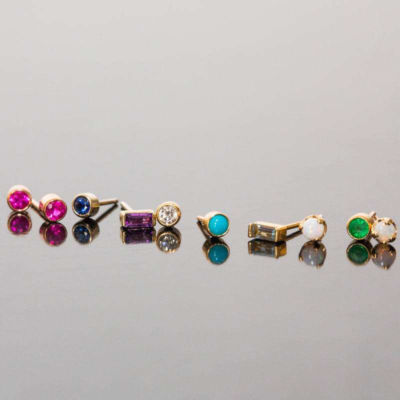row of single Zoe Chicco birthstone stud earrings laying