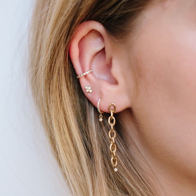 woman's ear wearing Zoë Chicco 14kt Gold Bezel Set White Diamond Ear Cuff with three other earrings