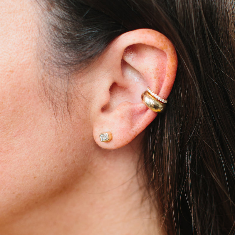 Close up of a woman's ear wearing a Zoë Chicco 14k Gold Emerald Cut Diamond Bezel Stud Earring