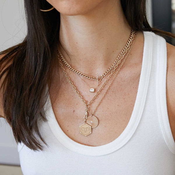woman in white tank wearing a Zoë Chicco 14k Gold 5 Diamonds Animal Hexagon Medallion Medium Square Oval Chain with Fob Clasp layered with other gold and diamond necklaces