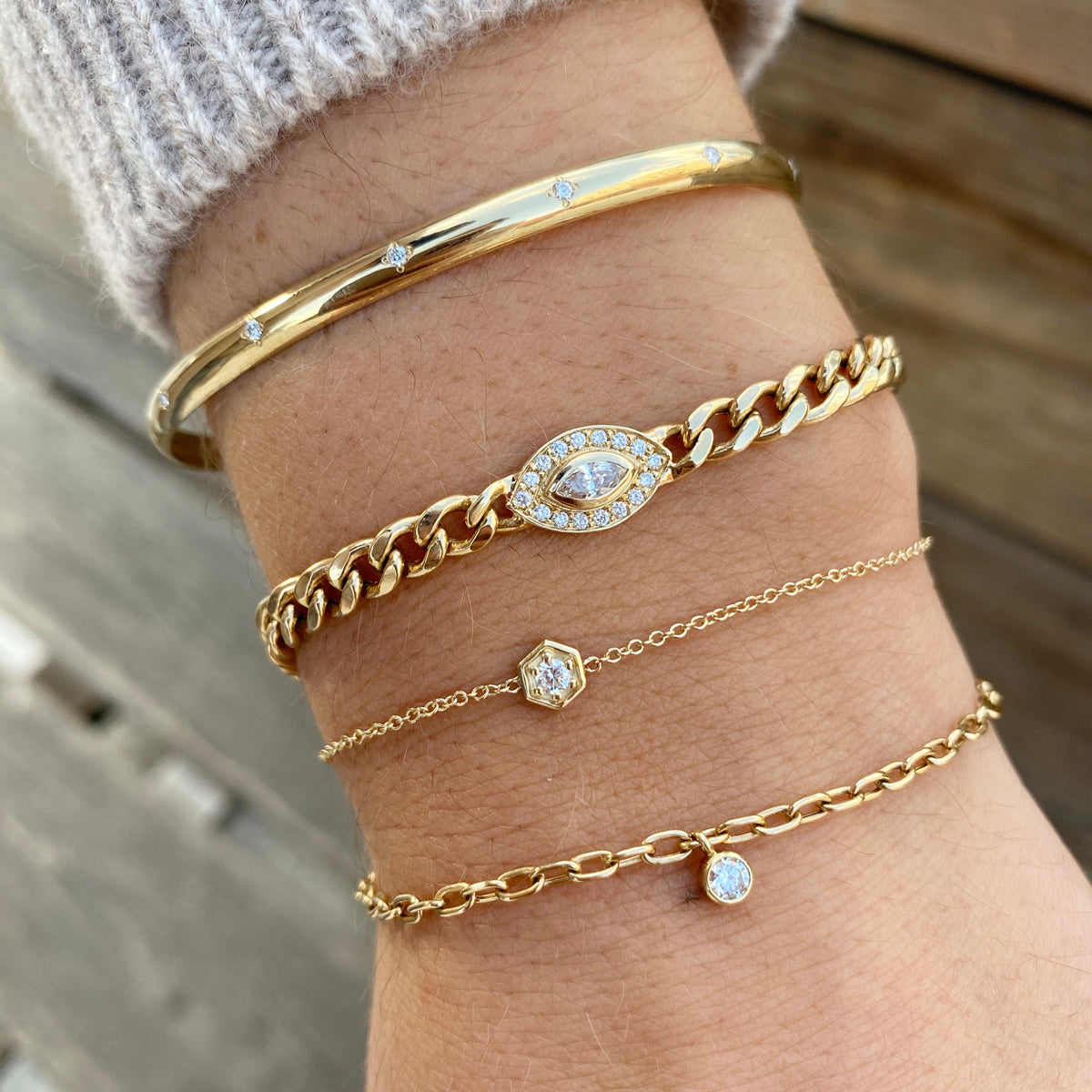 woman's wrist wearing Zoe Chicco 14kt Marquise Cut Diamond Halo Medium Curb Chain Bracelet with a Star Set Diamond Cuff, a Diamond Hexagon Bracelet, and a Diamond Bezel Square Oval Link Chain bracelet