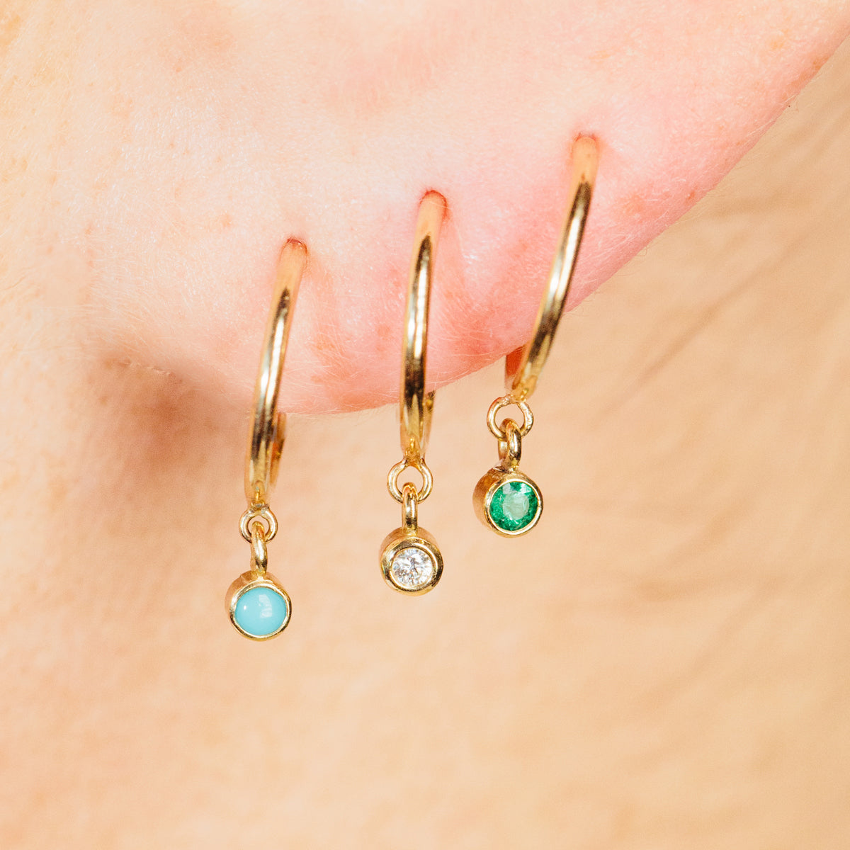 Woman's ear wearing zoe chicco birthstone hoops