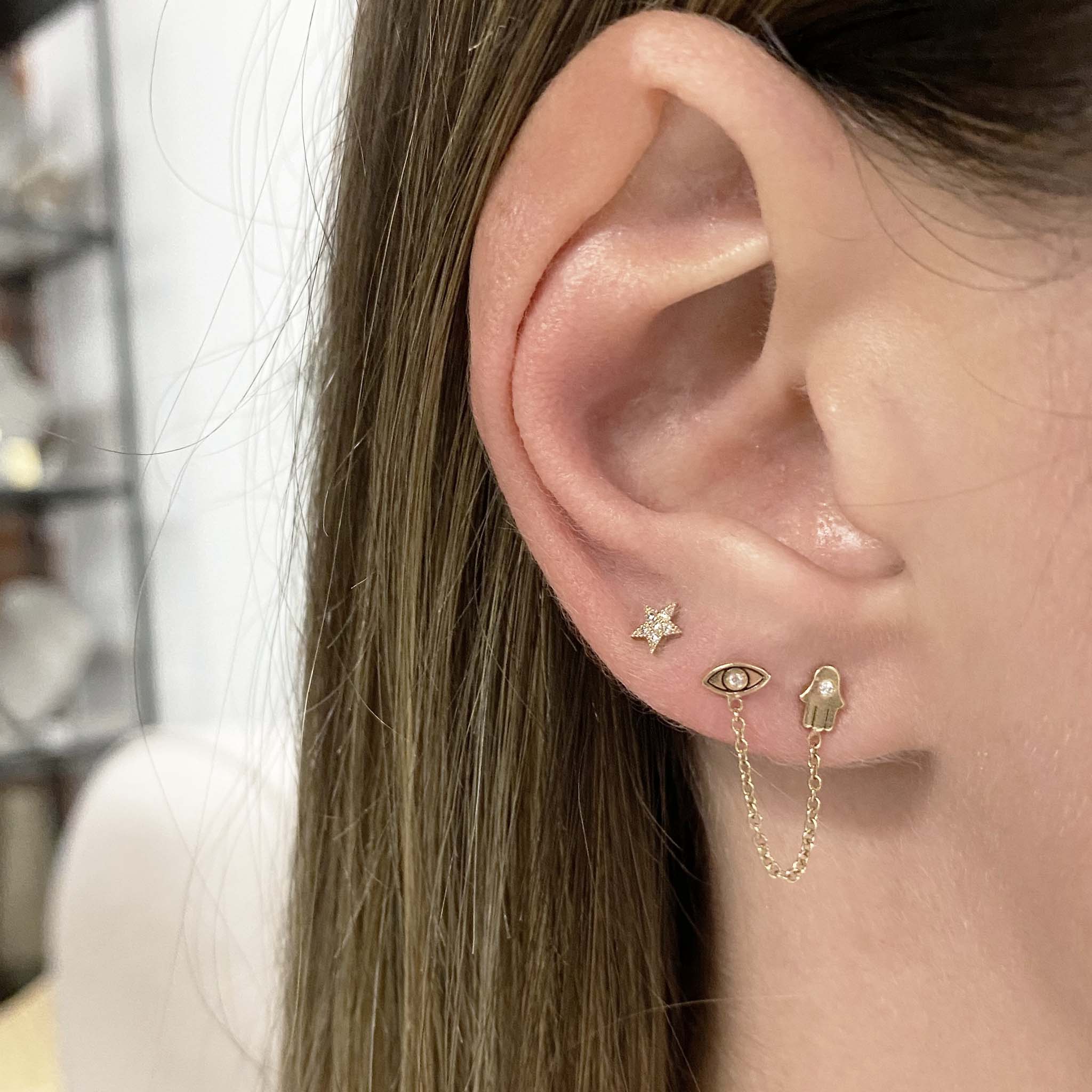 woman's ear wearing Zoë Chicco 14kt Gold Itty Bitty Pave Diamond Star Stud Earring