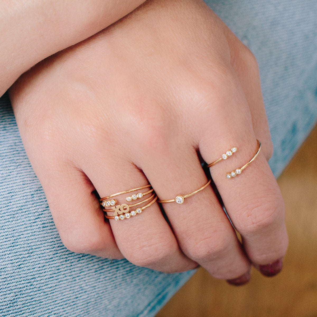 woman's hand wearing Zoë Chicco 14kt Gold Classic Thin Band Ring stacked with other gold and diamond rings