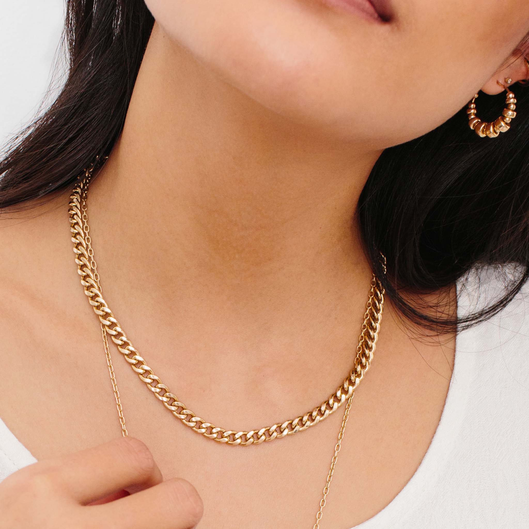 woman in white top wearing Zoë Chicco 14kt Gold Large Curb Chain Necklace layered with a long pearl pendant necklace