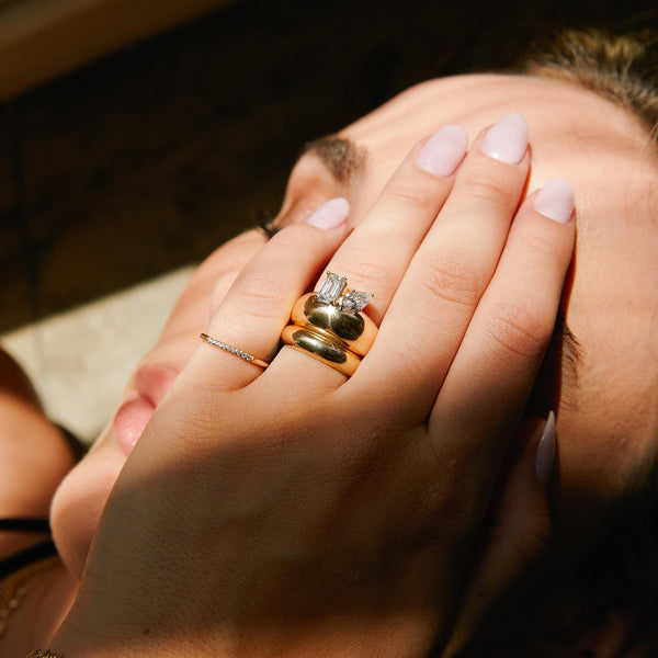 woman resting her hand over her face wearing a Zoë Chicco 14k Gold Large Pear & Emerald Cut Diamond Horizon Medium Aura Ring on her ring finger