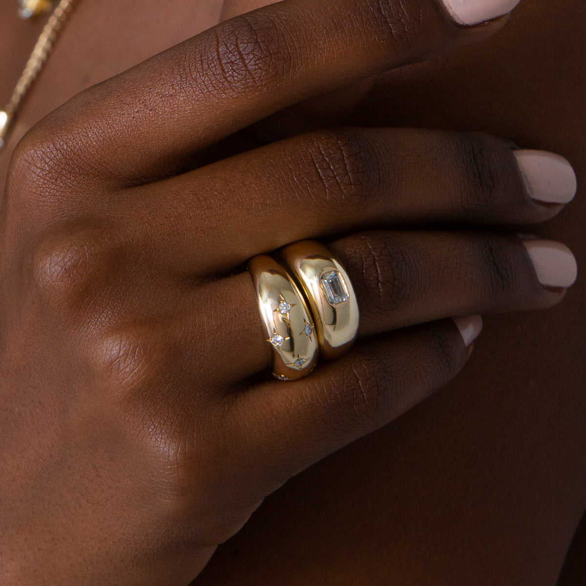 close up of woman's hand wearing Zoë Chicco 14k Gold Emerald Cut Diamond Medium Aura Ring stacked with a Star Set Diamond Aura Ring on her fourth finger