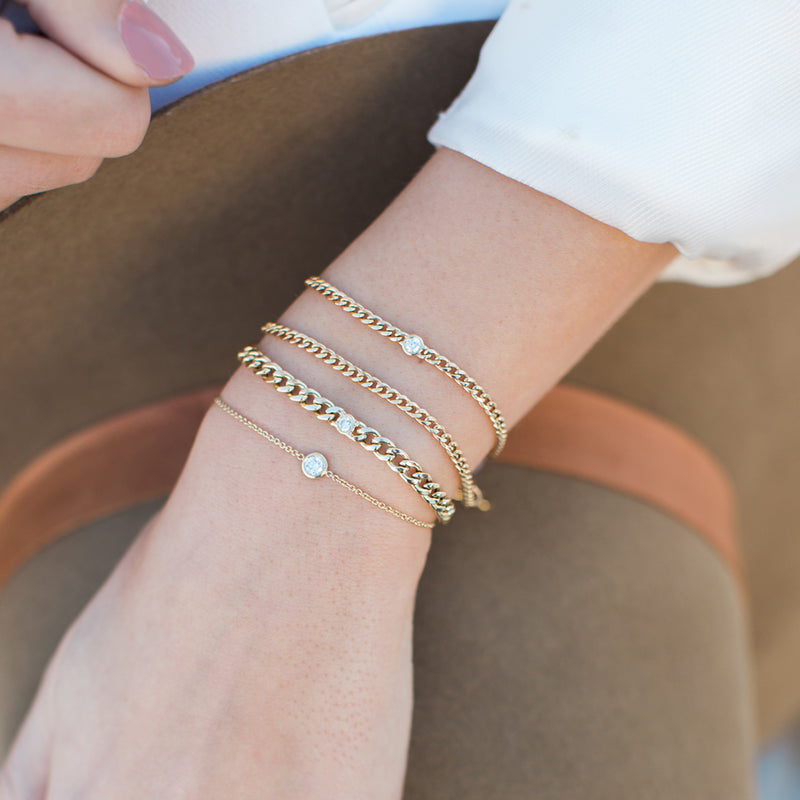Zoe Chicco 14kt Gold Single Floating Diamond Bracelet stacked with curb chain bracelets on a wrist