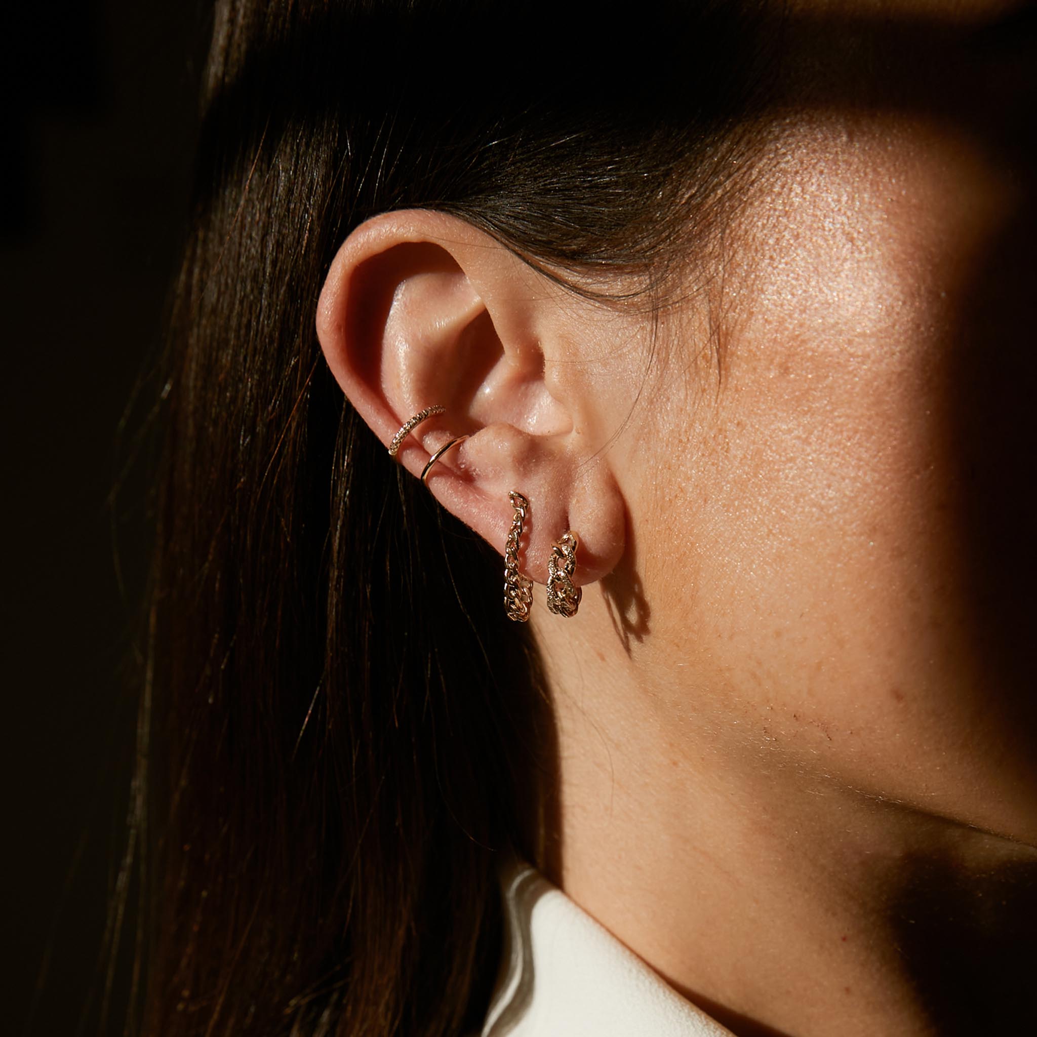 woman wearing a Zoe Chicco 14k Gold Mixed Wire Pave Diamond Double Ear cuff layered with a curb chain huggie and a pave diamond medium curb chain huggie hoop