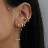 close up of woman's ear wearing a Zoë Chicco 14k Gold Spiked Hinge Huggie Hoop Earring layered with other gold and diamond earrings