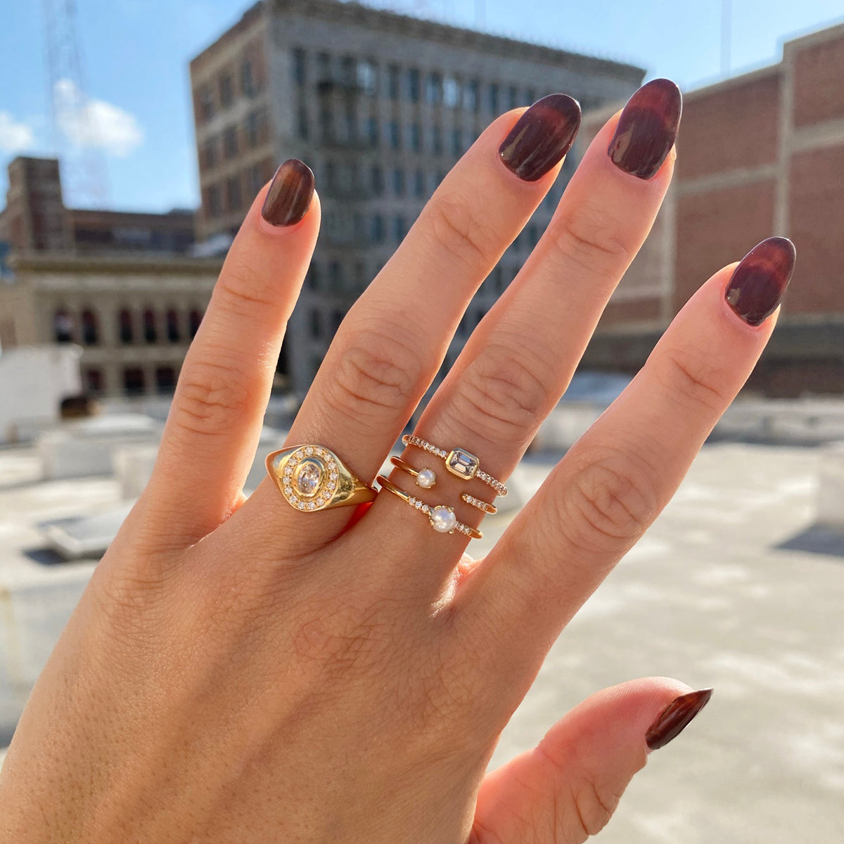 woman's hand wearing Zoe Chicco 14kt Gold Tiny Pearl & French Pave Diamond Open Ring stacked with two rings