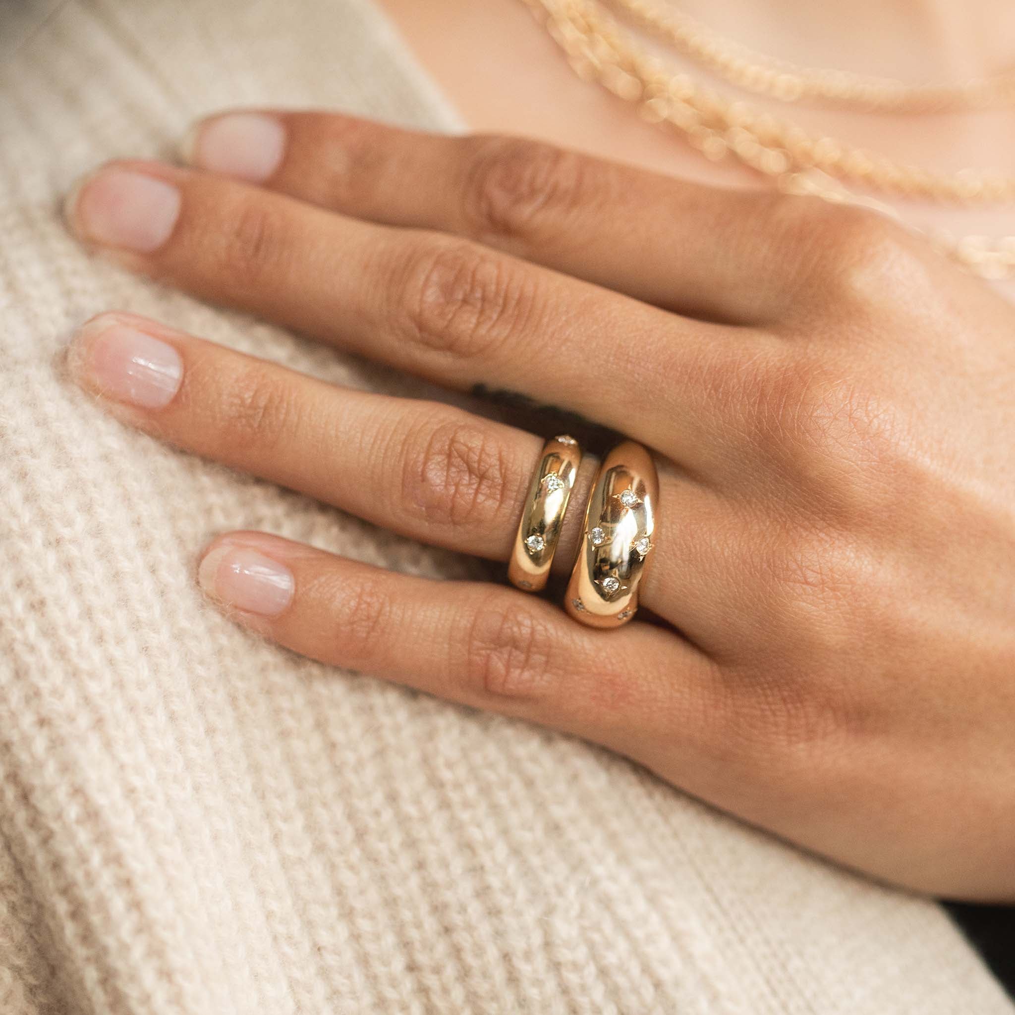 woman resting her hand on her shoulder wearing a Zoë Chicco 14k Gold Half Round Ring with 8 Star Set Diamonds stacked with a Scattered Diamond Medium Aura Ring