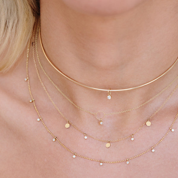 close up of a woman wearing a Zoë Chicco 14k Gold 11 Dangling Diamonds Bead Chain Necklace layered with three other necklaces
