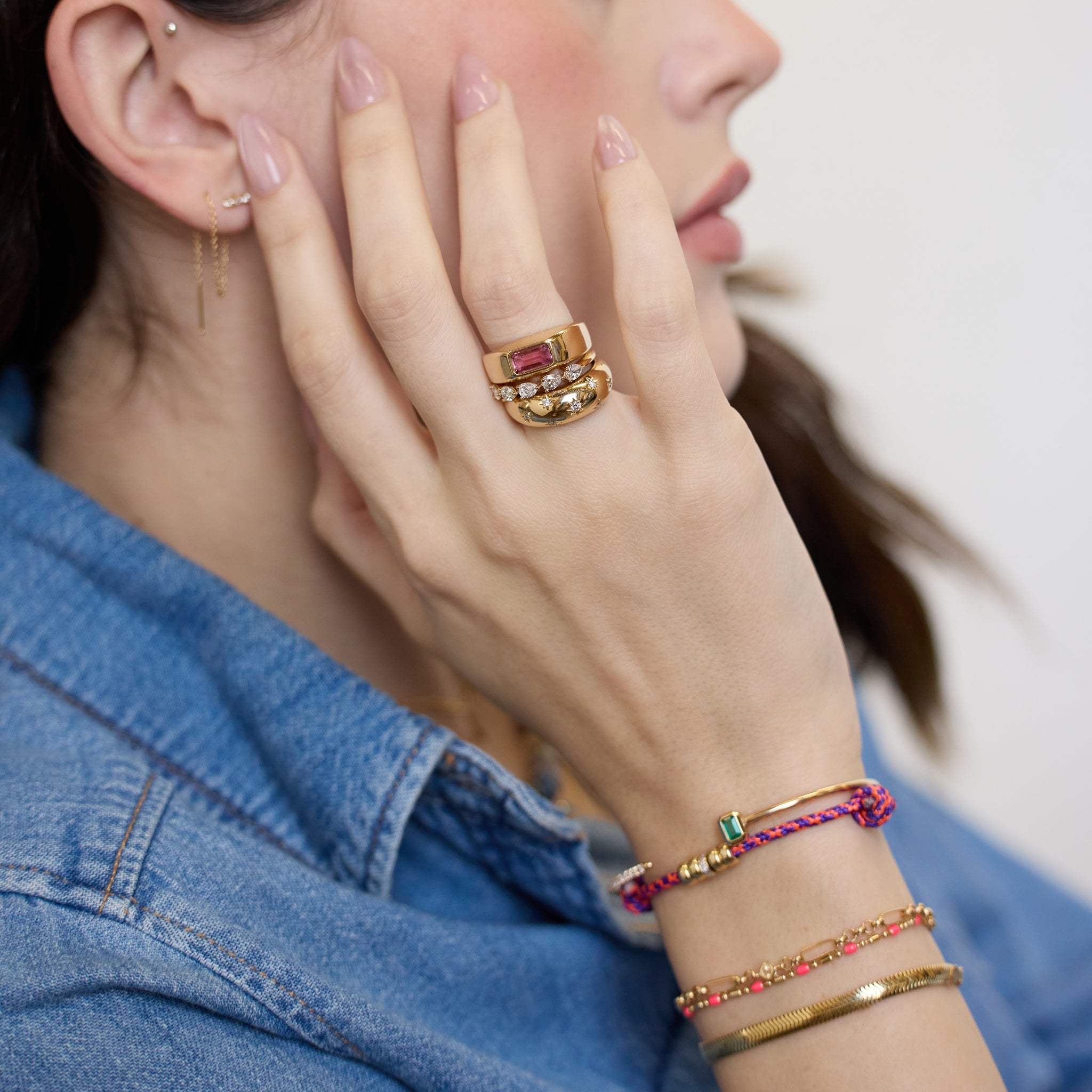 Zoe Chicco 14K woman wearing gold rings and bracelets with pink and diamond stones with a white background