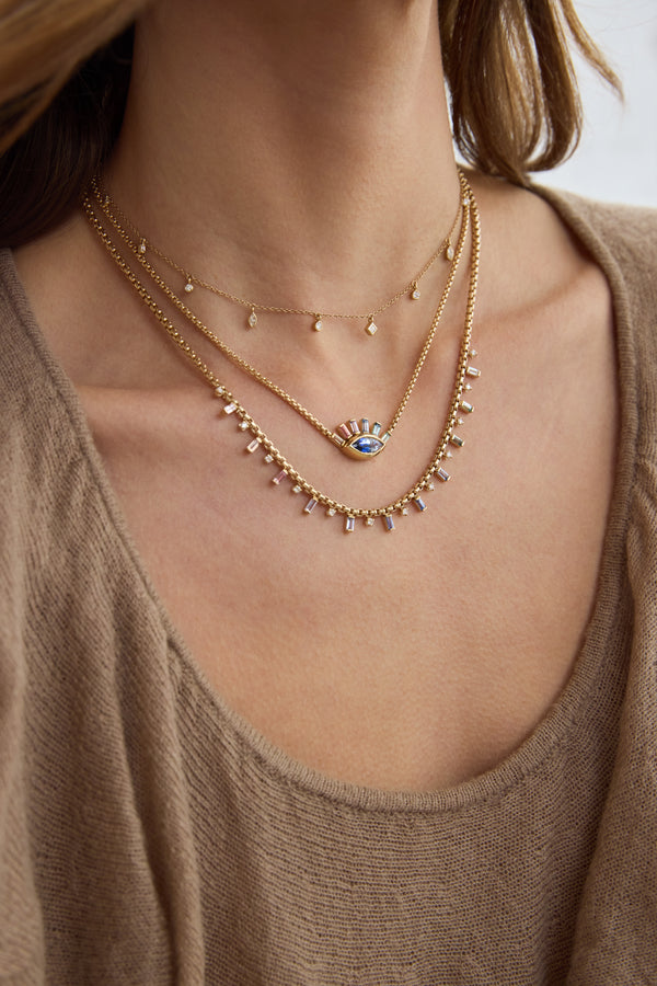 Zoe Chicco 14K Gold Close-up of a person wearing multiple delicate gold necklaces with small diamonds and gemstones on a plain background