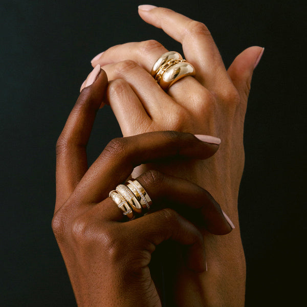 two woman's hands on a black background with one hand wearing Zoë Chicco 14k Gold Pavé Diamond Line Wide Flat Band on her fourth finger