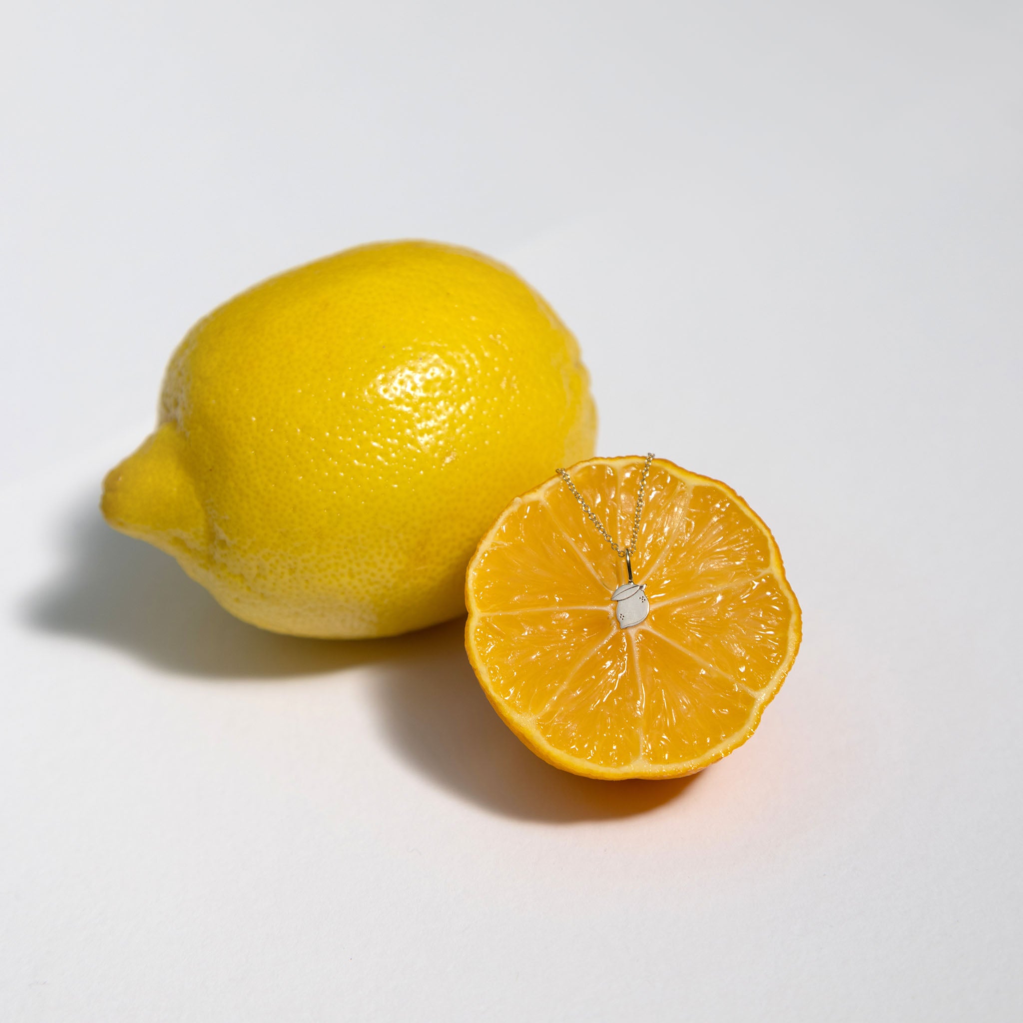 Lemon and orange citrus featuring a 14k gold Zoe Chicco lemon midi bitty charm chain necklace on a white background