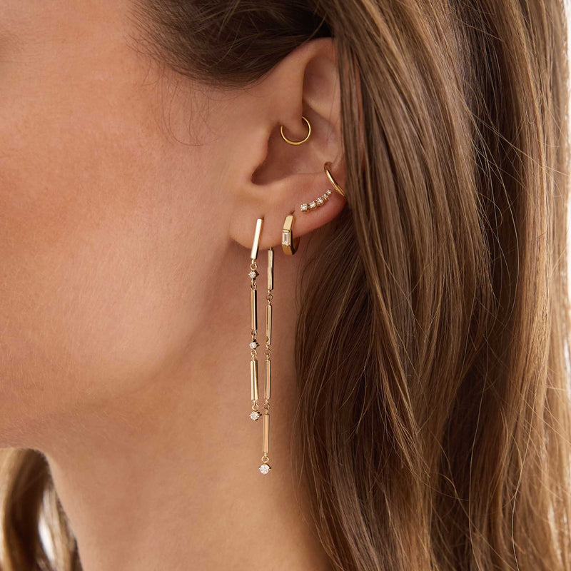 Zoe Chicco 14K  Close-up of an ear with gold earrings and a hoop earring.
