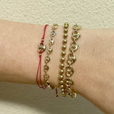 Gold bracelets on a wrist against a beige background