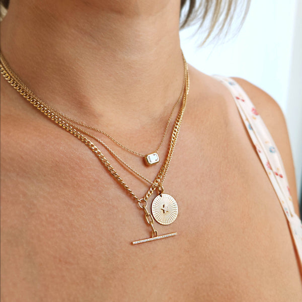 close up of a woman wearing a Zoë Chicco 14k Gold Pavé Diamond Star Small Sunbeam Medallion Necklace layered with two other necklaces