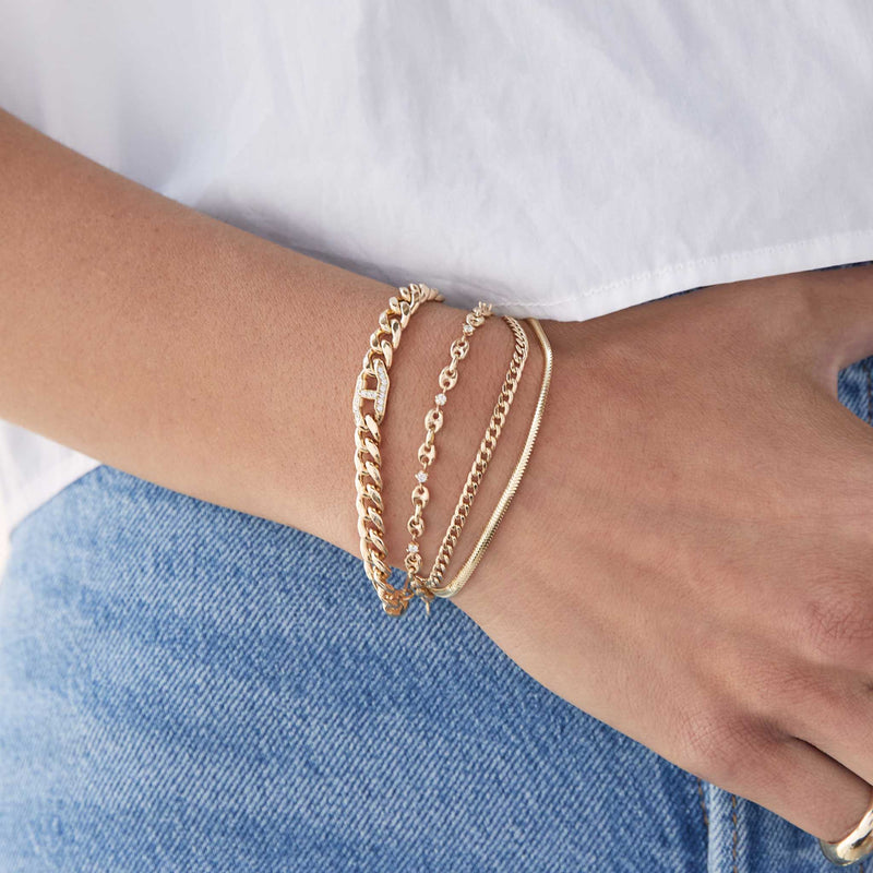 woman in a white tshirt and jeans wearing a Zoë Chicco 14k Gold Small Curb & Snake Double Chain Bracelet layered with a diamond mariner link bracelet and a Pave Diamond Mariner Link Large Curb Chain Bracelet