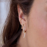 Angled view of a a brunette woman's ear wearing a Single Zoë Chicco 14k Gold Pavé Diamond Talon Earring layered with a Diamond Ice Pick Stud