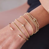 woman's wrist wearing a Zoë Chicco 14k Gold Pear Diamond Bead Chain Bracelet stacked with a Small Snake Chain Bracelet, 
14k 3 Diamond Bezel Bar Open Cuff, 14k Diamond Bezel Tennis Segment Bead Chain Bracelet, and a Paperclip Box Chain Wrap Bracelet