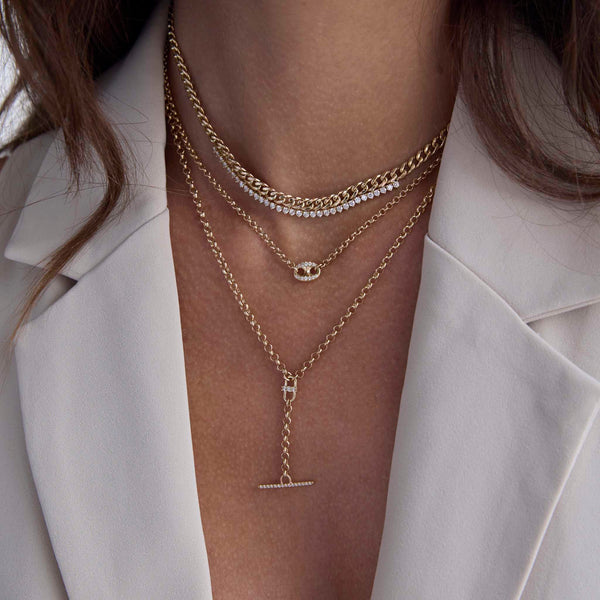 woman in a cream blazer wearing a Zoë Chicco 14k Gold Large Pavé Diamond Mariner Link Rolo Chain Necklace layered with a 14k 3 Prong Diamond Open Link Pavé Diamond Toggle Rolo Chain Lariat and a Diamond Curb Chain Necklace